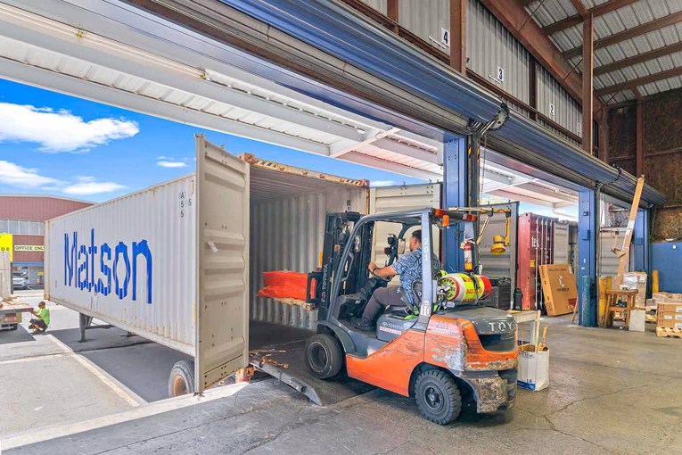 Forklift driver unpacking shipping container